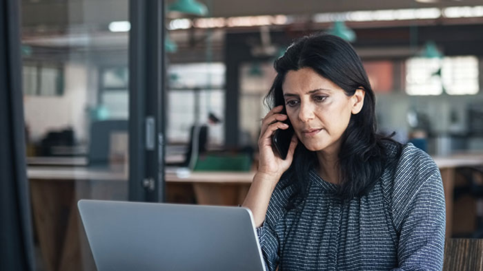 Woman on cell phone looking at laptop